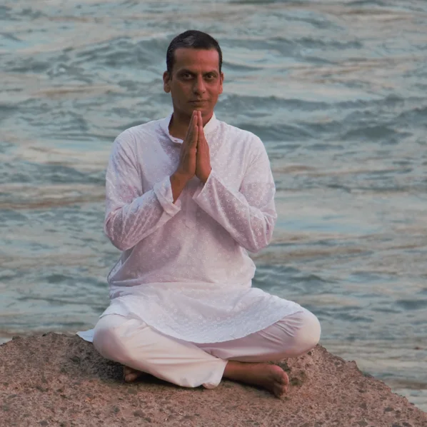Yogi Shri G. Niranjan seated in meditation by the water